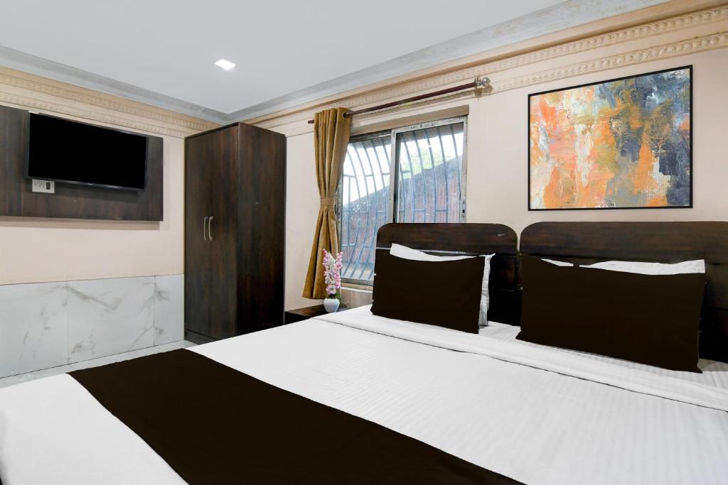 een slaapkamer met een groot bed en een televisie bij Hotel O AK International Hotel in Calcutta