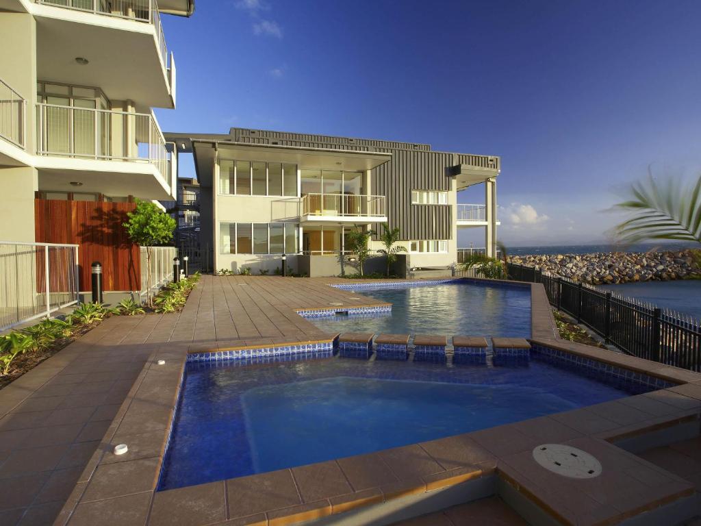 a swimming pool in front of a house at Grand Mercure Apartments Magnetic Island in Nelly Bay