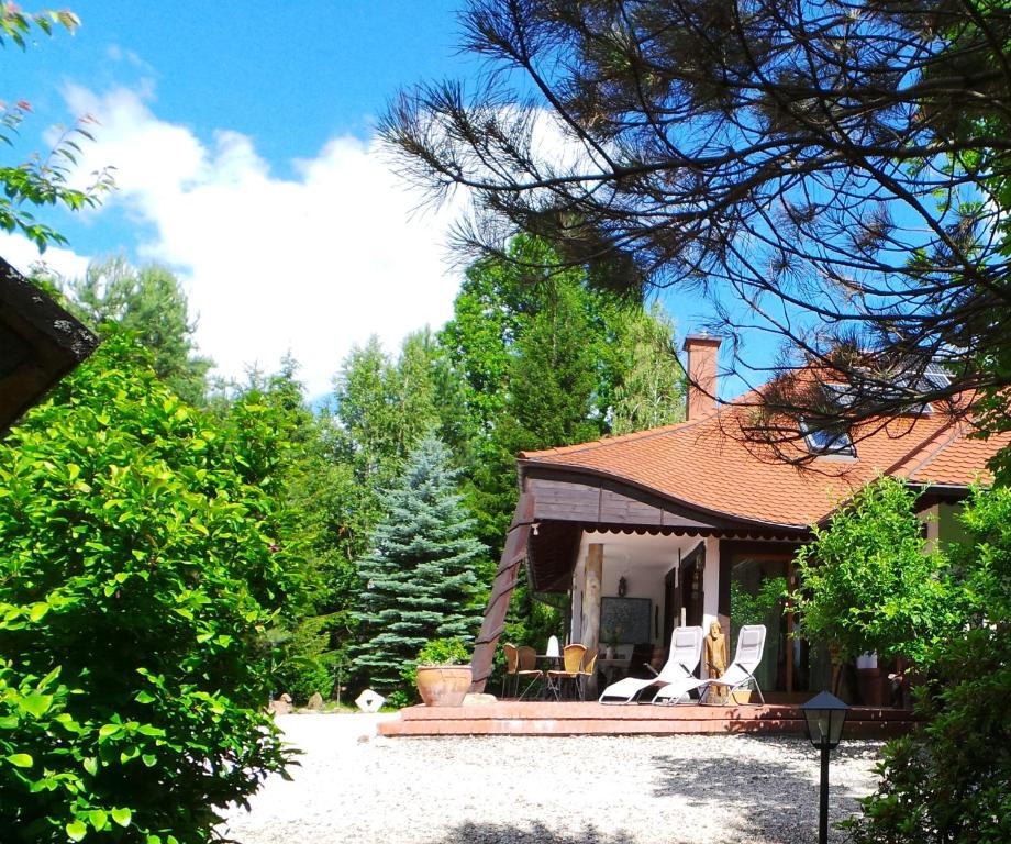 DziwiszówDom na Leśnym Zaciszu 2的一栋带门廊的房子，门廊上摆放着白色椅子，还有树木。