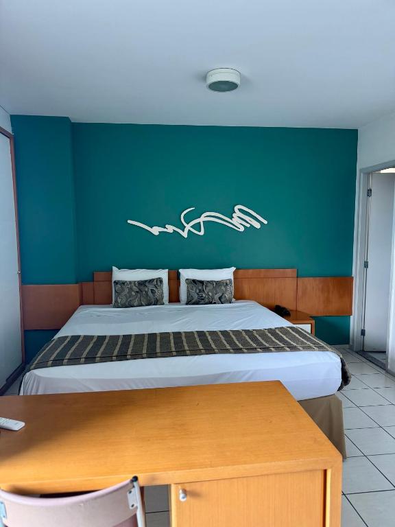 Un dormitorio con una cama con una pared verde. en Praia do Canto Apart Hotel Varanda frente mar, en Vitória