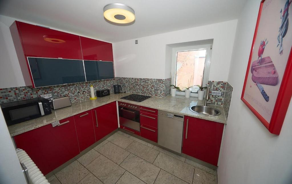 a small kitchen with red cabinets and a sink at gemütliche 4 Zimmer Wohnung mit Einzelbetten, Küche und Badezimmer in Hohenmölsen