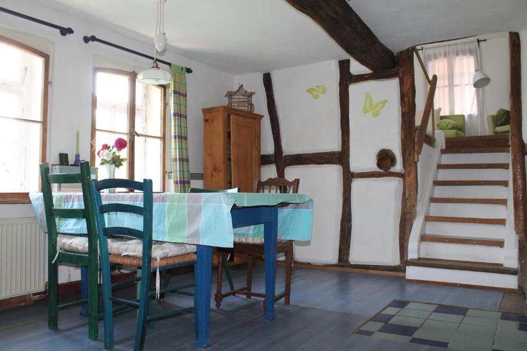 a dining room with a blue table and chairs at Maison Mille Fleurs in Sankt Julian-Obereisenbach