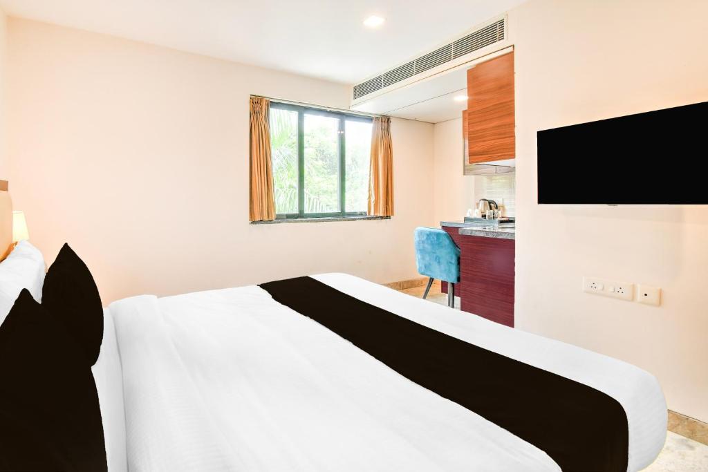 バラナシにあるTownhouse OAK Hotel Naman Studioのベッドとテレビがあるホテルの部屋