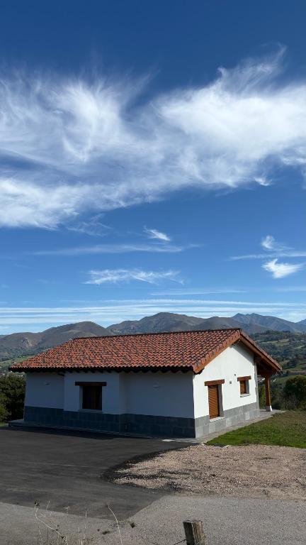 ein weißes Gebäude mit rotem Dach auf einem Parkplatz in der Unterkunft Casa de Aldea EL AVELLANU in Bierces