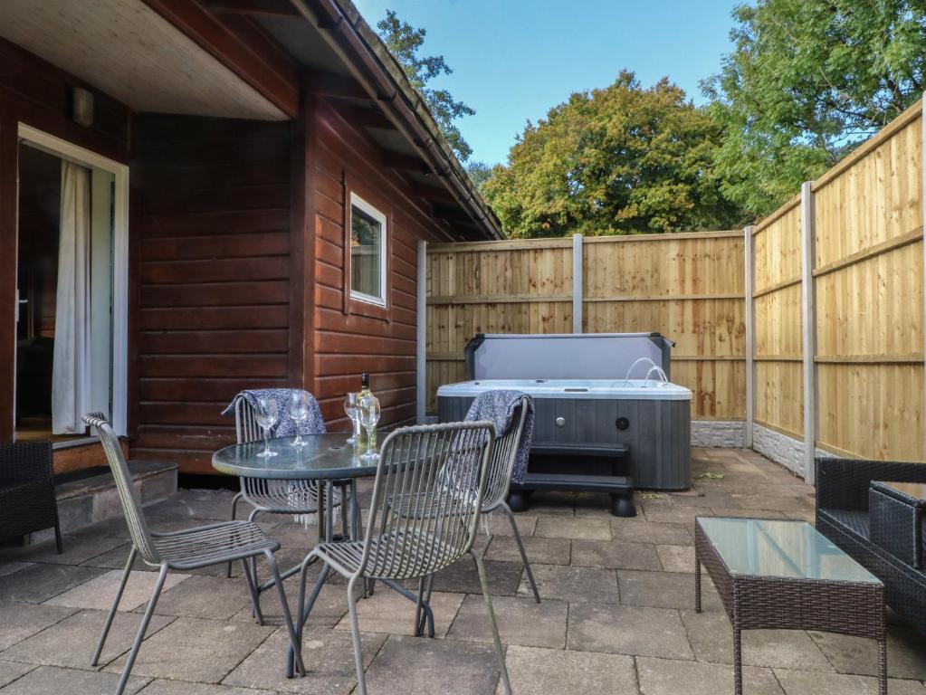 a patio with a table and chairs and a grill at Woodlands View in Leek