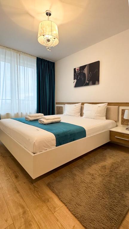 a bedroom with a large white bed with a chandelier at VENUS Studios at Coresi Mall in Braşov