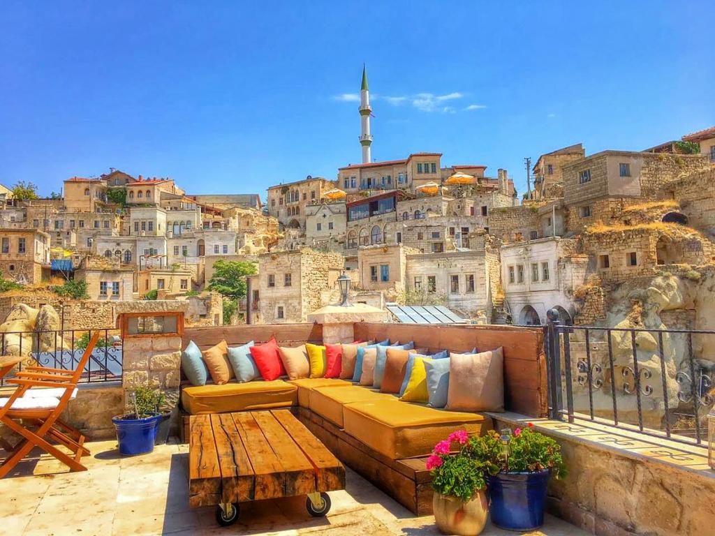 a couch on a balcony with a view of a city at Elaa Cave Hotel in Ortahisar