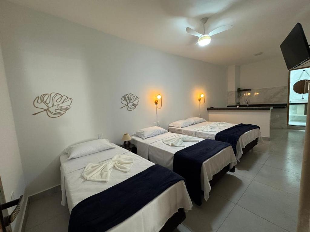 een kamer met 3 bedden en een plafondventilator bij Hey Mar Suites in Arraial do Cabo