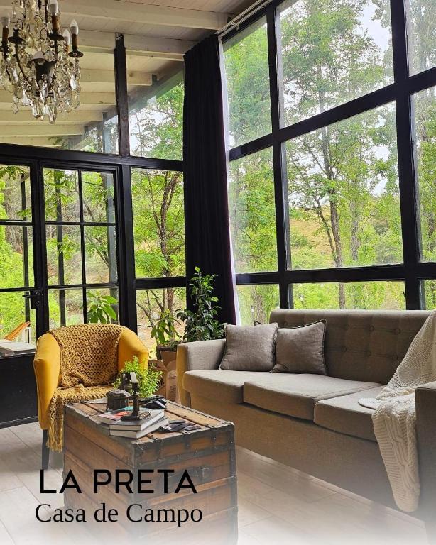 een woonkamer met een bank en grote ramen bij La Preta, casa de campo in San Clemente