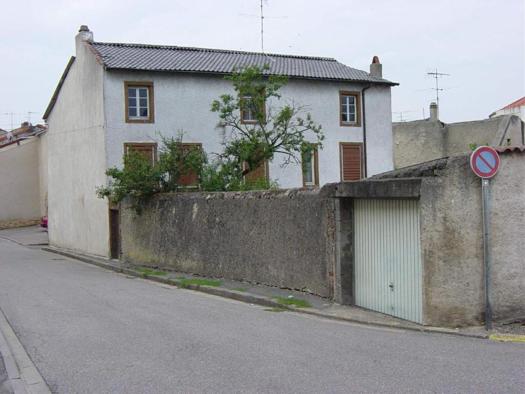 a white building with a garage next to a wall at Louise's Loft in Boulay - Moselle