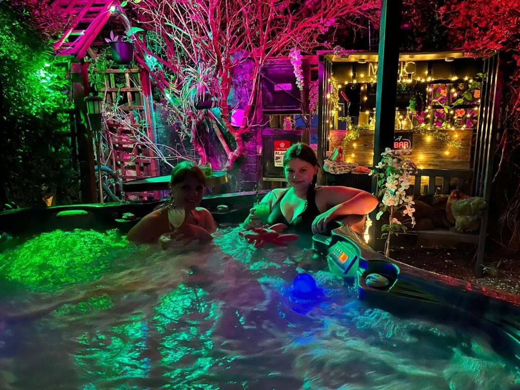 Dos mujeres sentadas en una piscina en una fiesta. en The Stable Annexe with hot tub & horses, en Dogdyke
