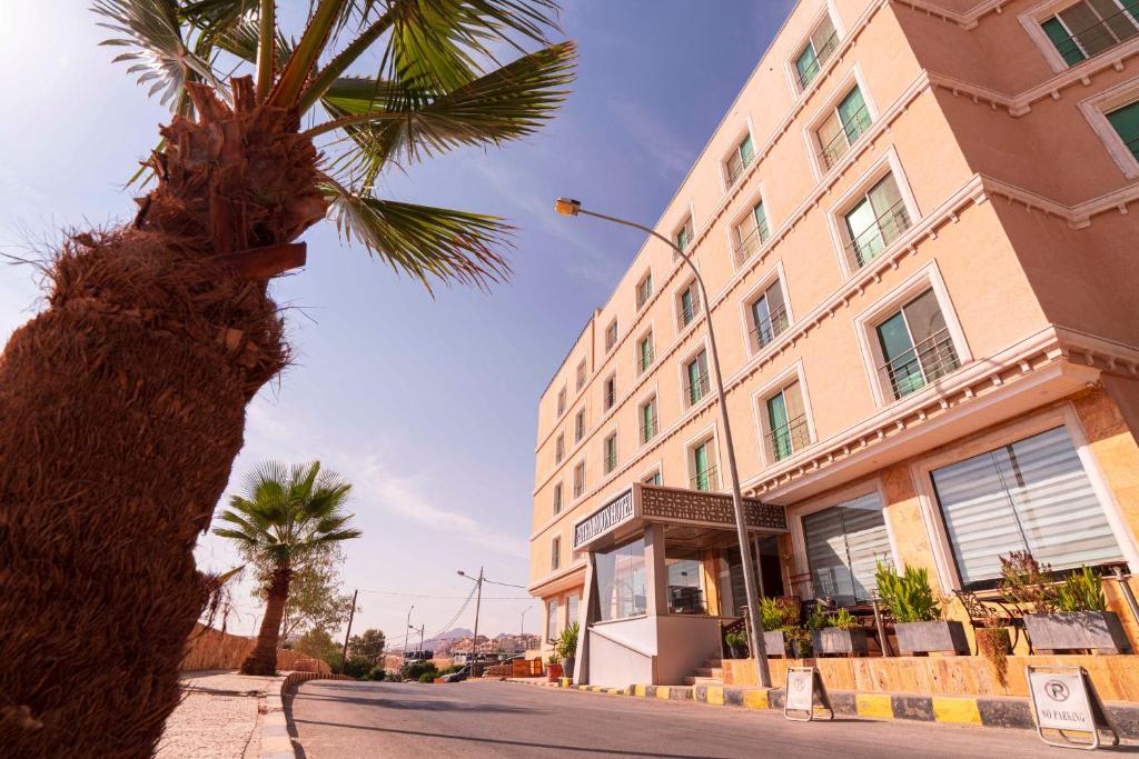 a palm tree in front of a tall building at Petra Moon Hotel in Wadi Musa