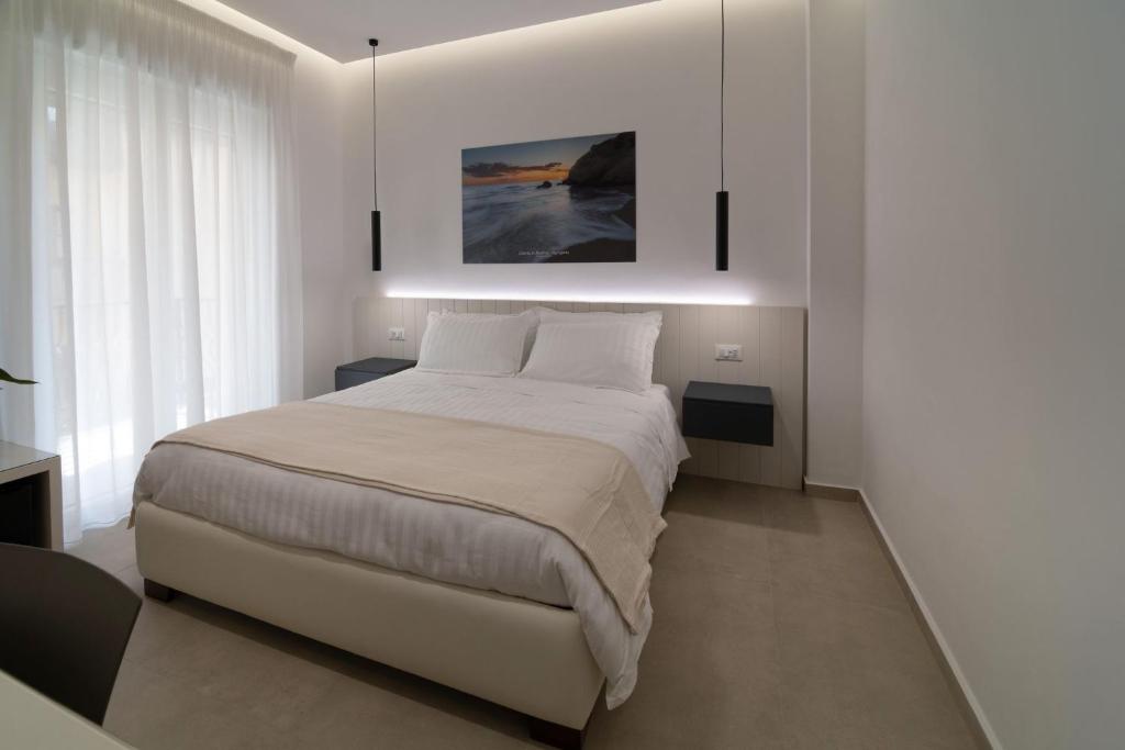 a white bedroom with a bed and a painting on the wall at B&B Cariddi Rooms in Caltanissetta