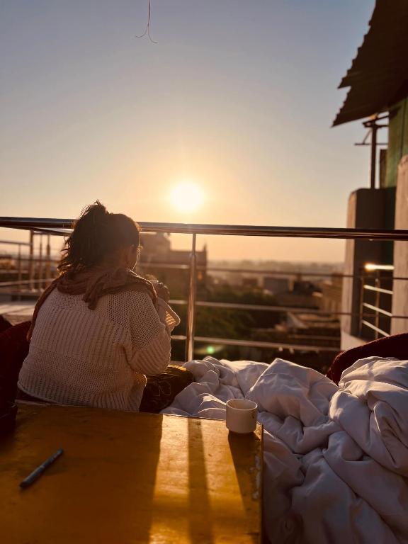 斋沙默尔Jaisalmer Hostel Dara的一位女子坐在桌旁欣赏日落。