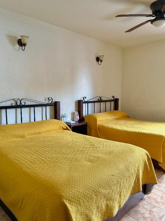 two beds in a room with yellow sheets at Hotel Uke Inn Terán in Tuxtla Gutiérrez