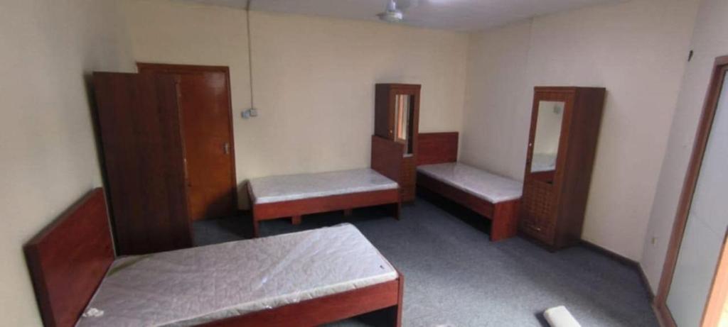 沙迦masqat building的带三张床和镜子的房间