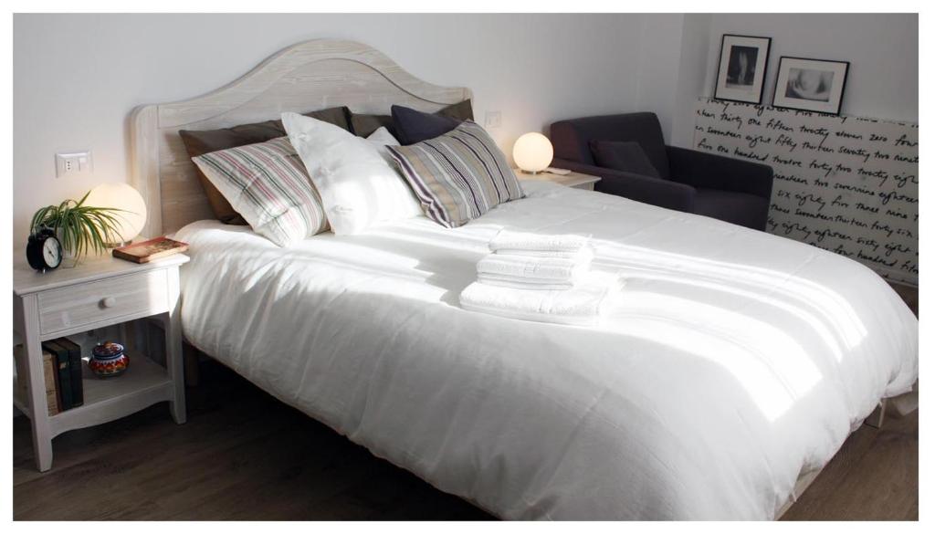 a large white bed in a bedroom with a chair at A Cjase di Lise in Gemona del Friuli