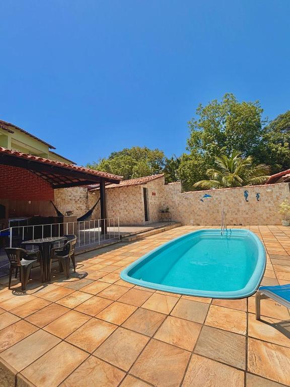 a swimming pool on a patio with a table and chairs at Refúgio Amor de Mãe in Araruama