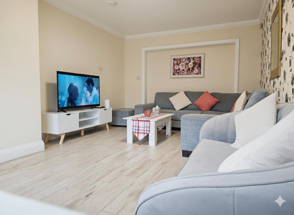 a living room with a couch and a tv at Spacious Modern 5 bedroom home near Heathrow Windsor in Canvey