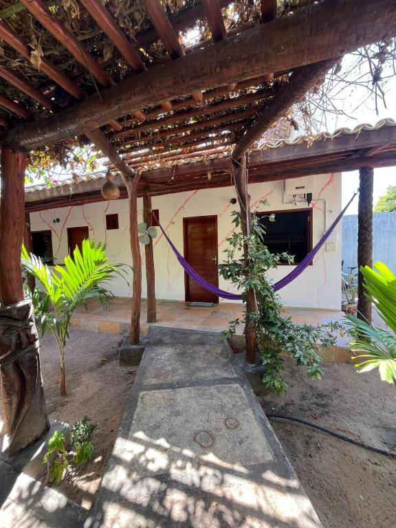 a house with a hammock hanging from a pergola at Pousada Imperio dos Bambus in Jijoca de Jericoacoara