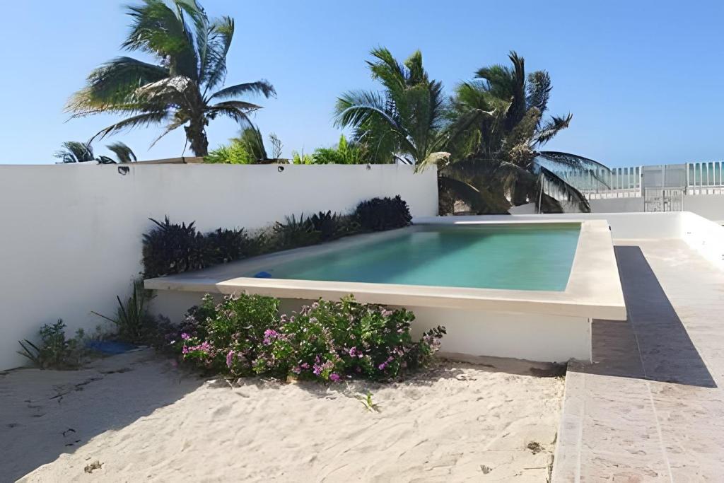 a swimming pool in the sand next to a white wall at Villa del Mar, un espacio funcional y bien ubicado in Progreso