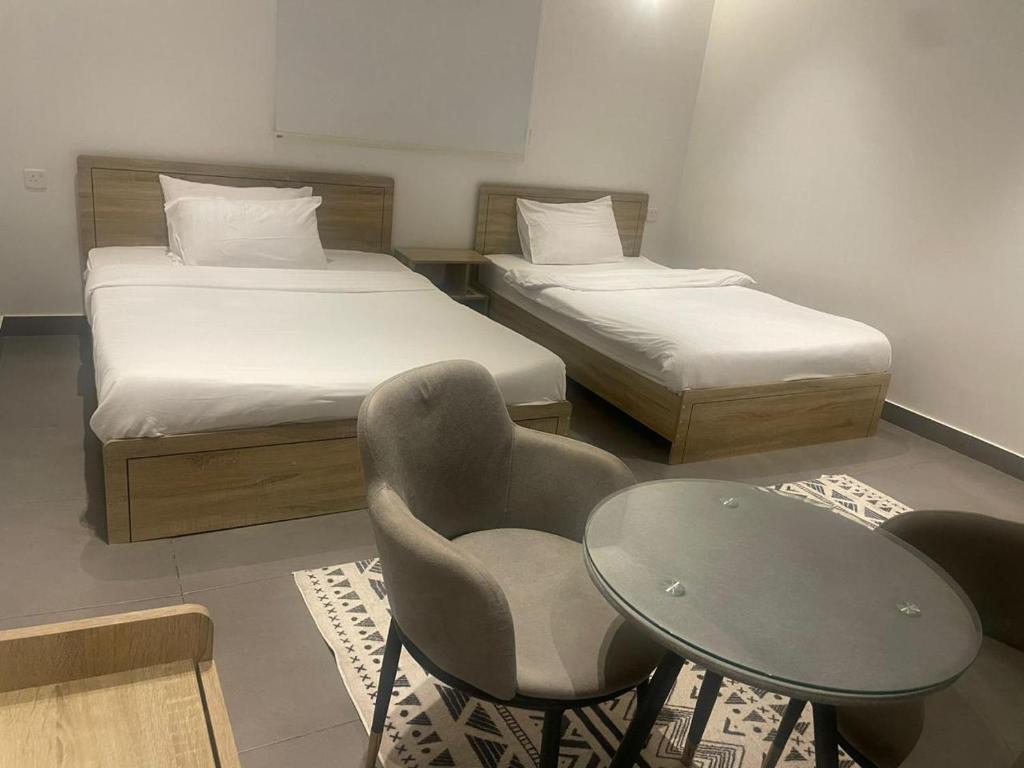 a room with two beds and a table and a chair at Najd Hotel in AlUla