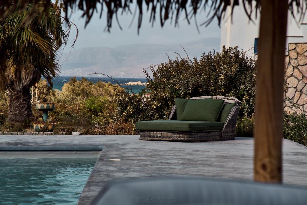 Diamantis Kitesurf Residencies في ميكري فيغلا: كرسي أخضر يجلس على فناء بجوار حمام السباحة