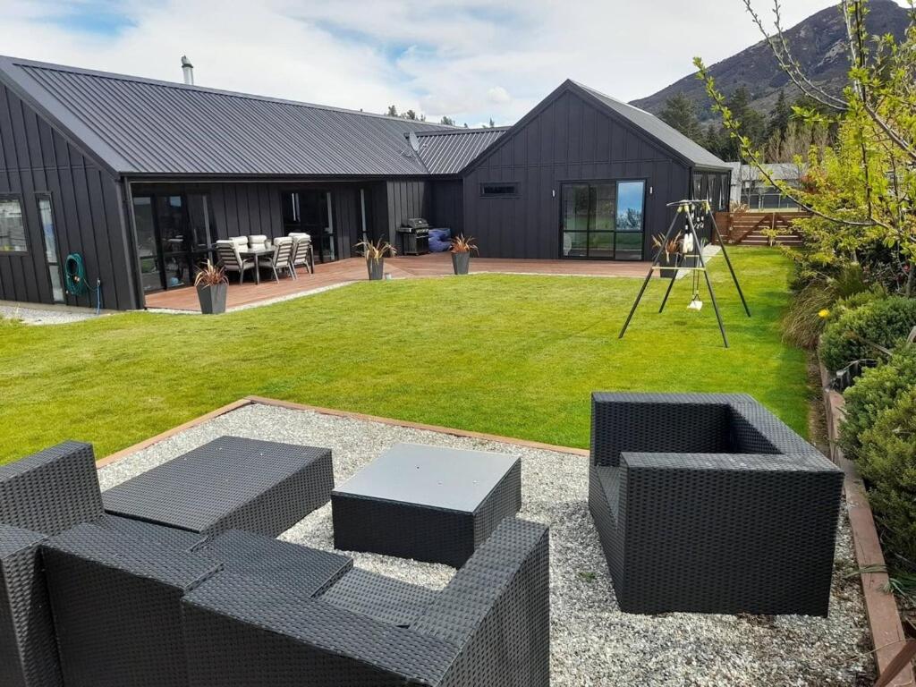 a backyard with a black couch and a table at Beautiful Home in Lake Hawea in Lake Hawea