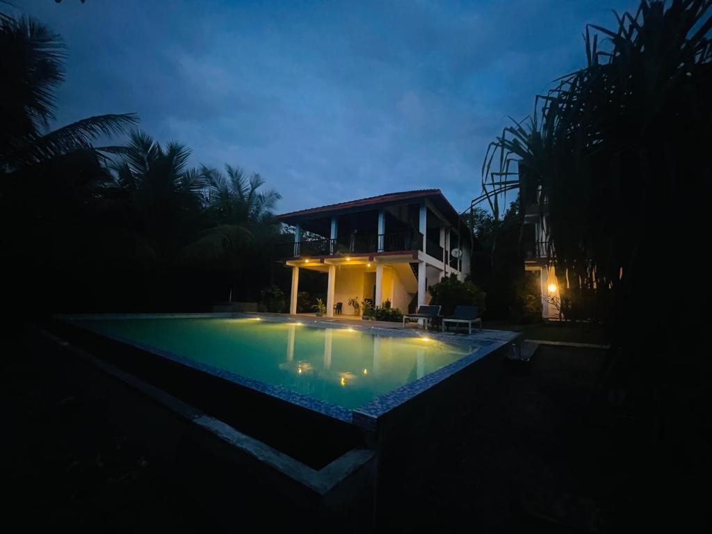 Ashansa Lagoon Resort في تانجالي: منزل به حمام سباحة في الليل