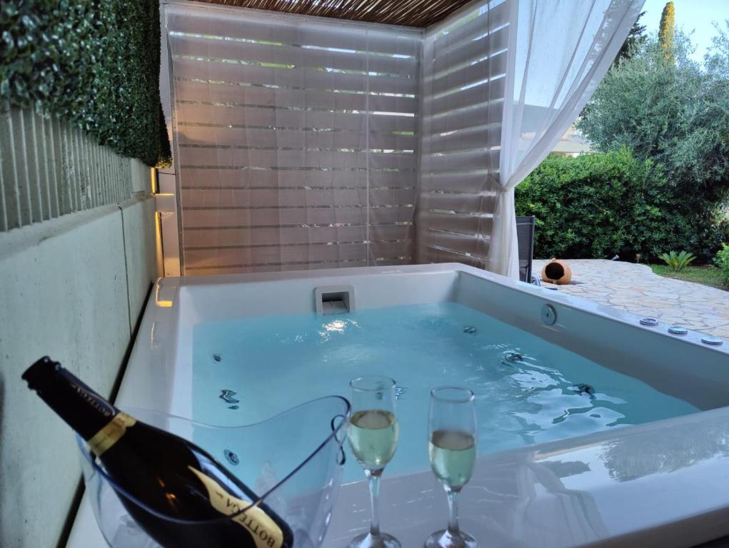 una bottiglia di vino e due bicchieri in una vasca idromassaggio di Nefeli Beach Home a Barbati