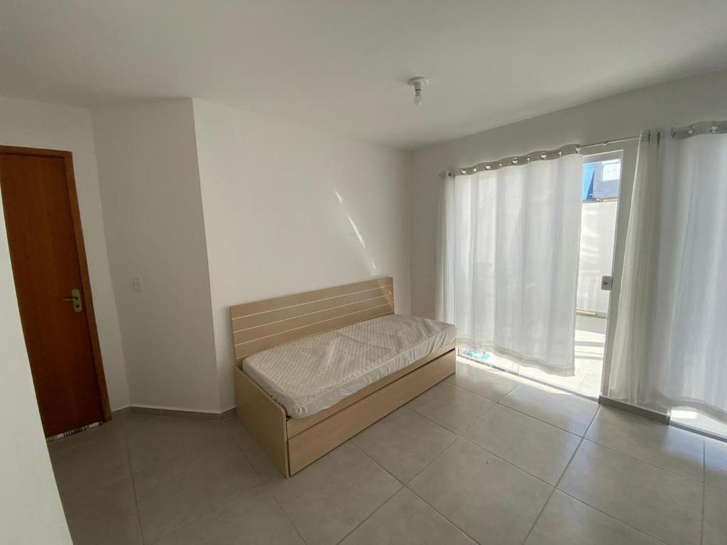 a bed in a room with a large window at Apartamento do Peró in Cabo Frio