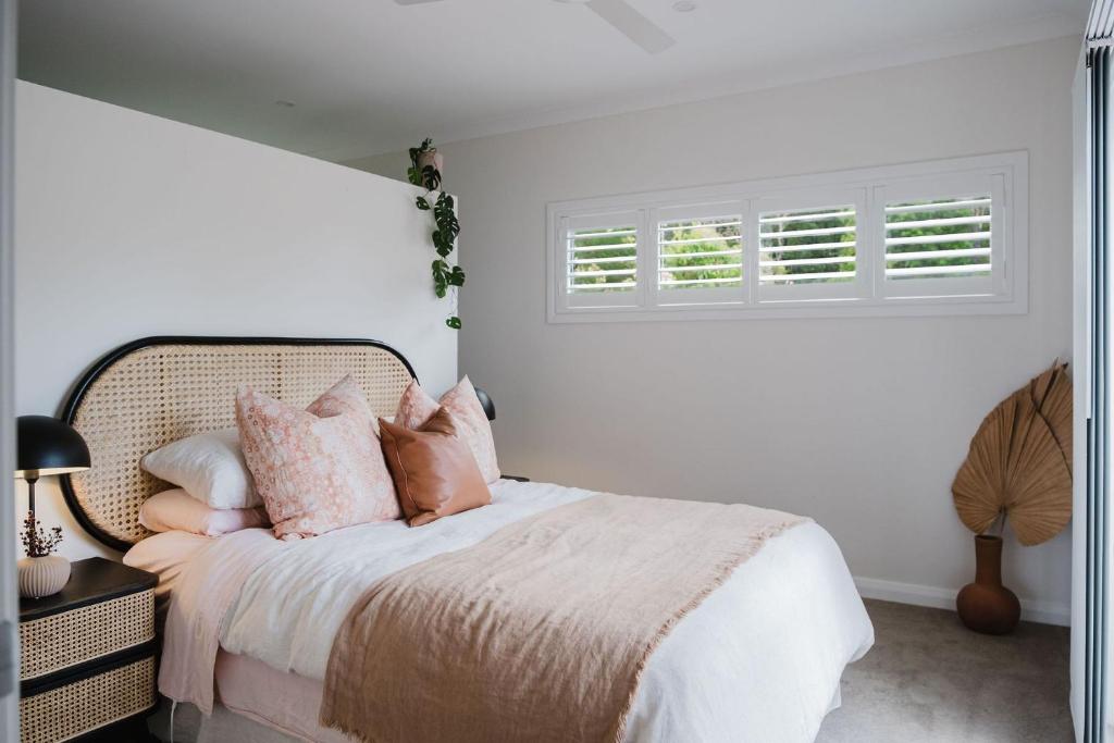 Habitación blanca con cama con almohadas rosas en The Lake Escape, en Yatte Yattah