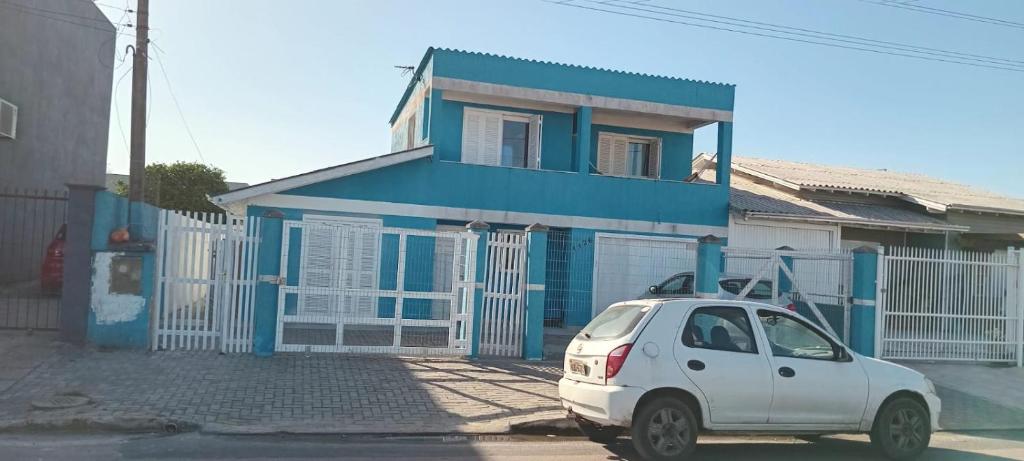 una macchina bianca parcheggiata di fronte a una casa blu di Aluguel casa azul a Capão da Canoa