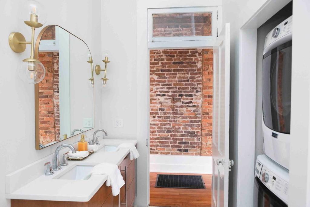 a bathroom with a sink and a brick wall at East Main Your Merry Modern Downtown Getaway in Bowling Green