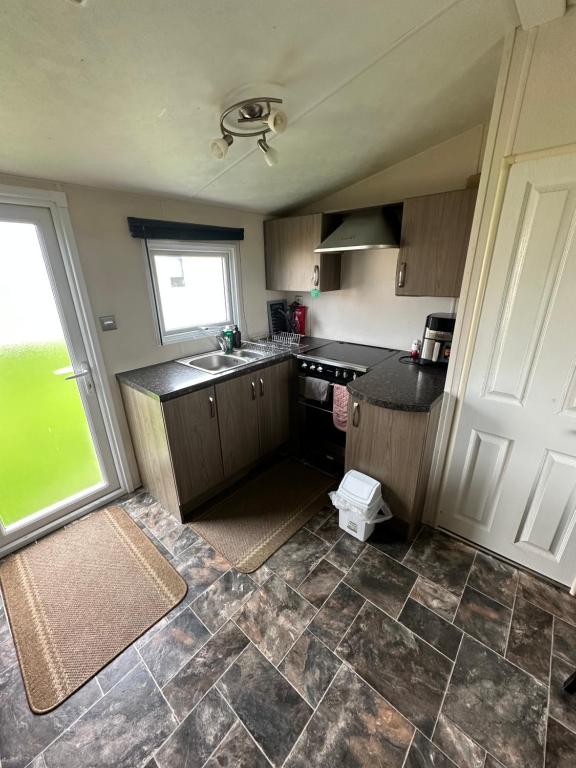 Una pequeña cocina con fregadero y ventana. en 16 orchid meadows, en Ashington