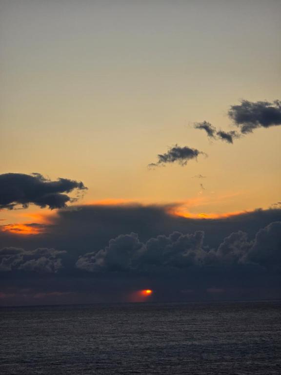 einen Sonnenuntergang über dem Meer mit der Sonne hinter Wolken in der Unterkunft Cimarte The Path Lukove in Lukova