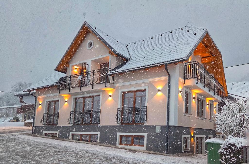 ein schneebedecktes Haus mit Lichtern in der Unterkunft Alpine House Mina - Rooms & Apartments in Bled