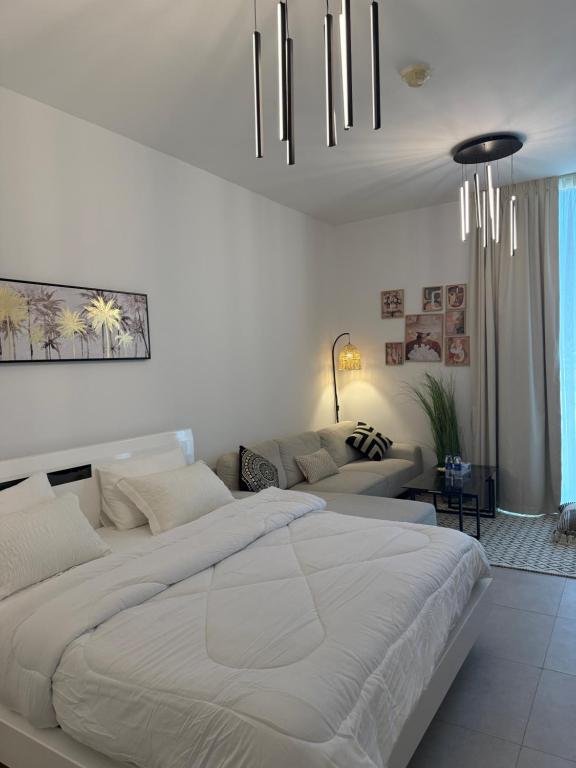 a white bedroom with a large bed and a couch at Beautiful studio at aljada community in Sharjah