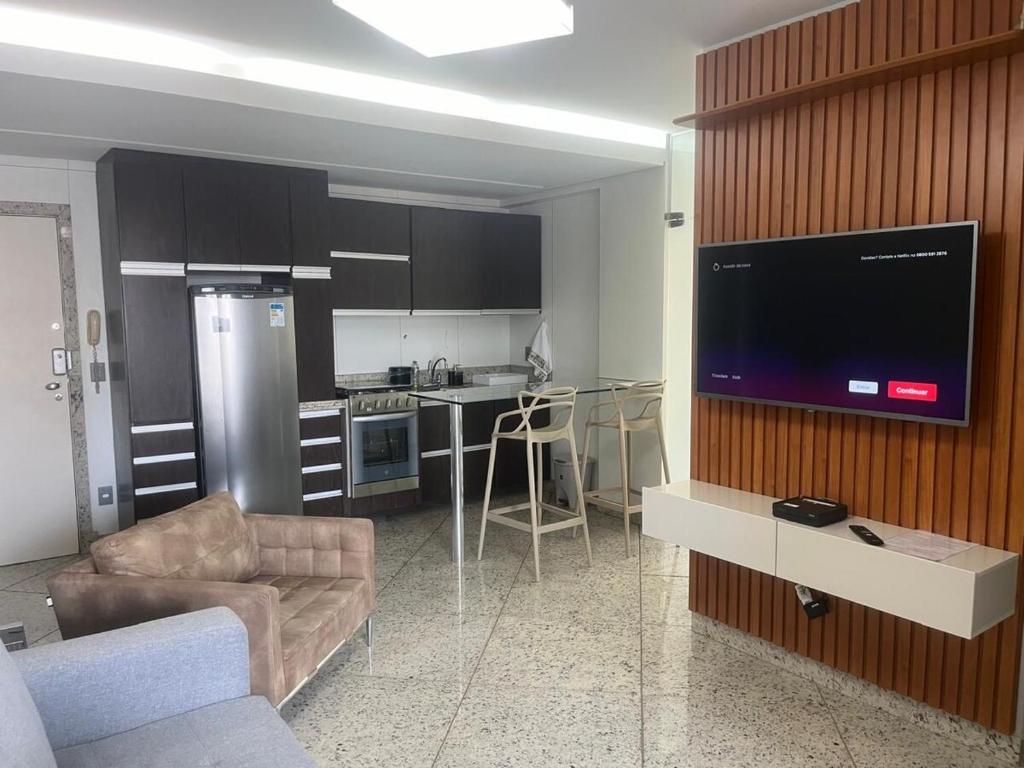Beautiful apartment in Vila da Serra في نوفا ليما: غرفة معيشة ومطبخ مع تلفزيون كبير على الحائط
