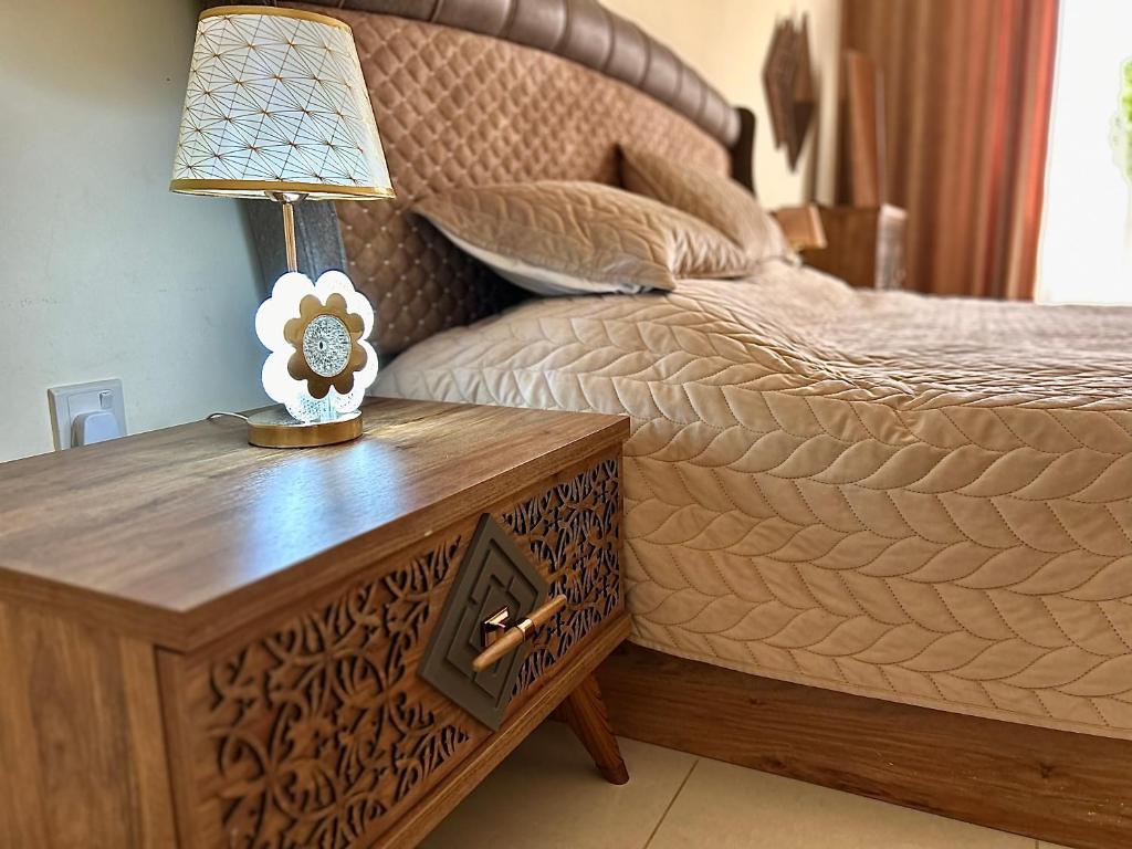 a bedroom with a bed and a table with a lamp at Bab Al Bahr 2 BR Apartment in Ras al Khaimah