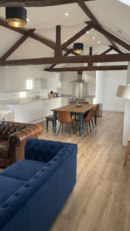 a living room with a blue couch and a table at Eastfields Farm Barns in Melchbourne