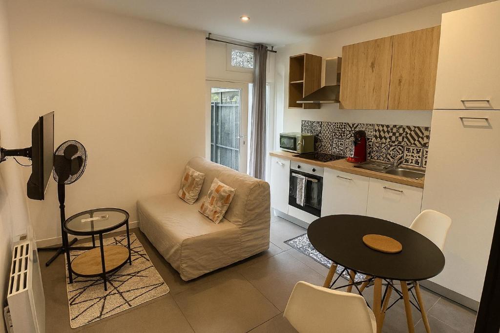 ein Wohnzimmer mit Sofa und Tisch in der Unterkunft Studio Rénové tout équipé au calme proche des commerces in Briord