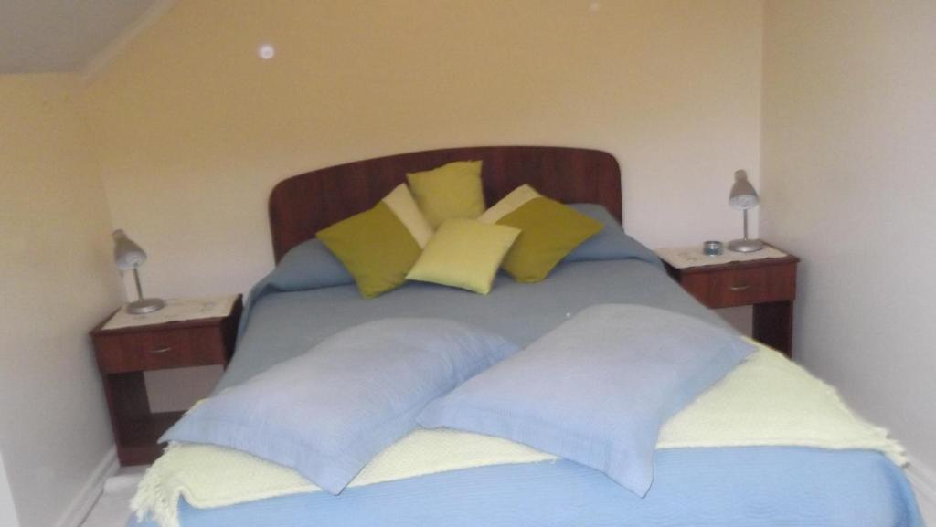 Una cama con almohadas azules y amarillas. en Departamento Duplex Centro Pucon, en Pucón