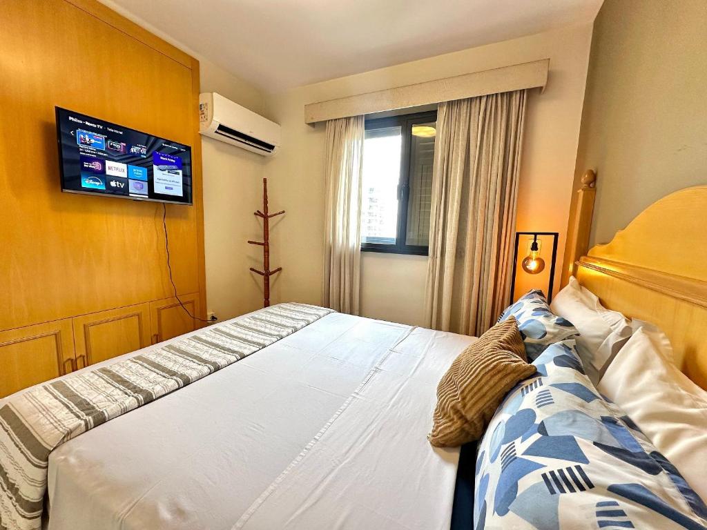 a bedroom with a bed and a tv on the wall at Flat luxo, Janela Antirruído, Garagem, serviços in São Paulo