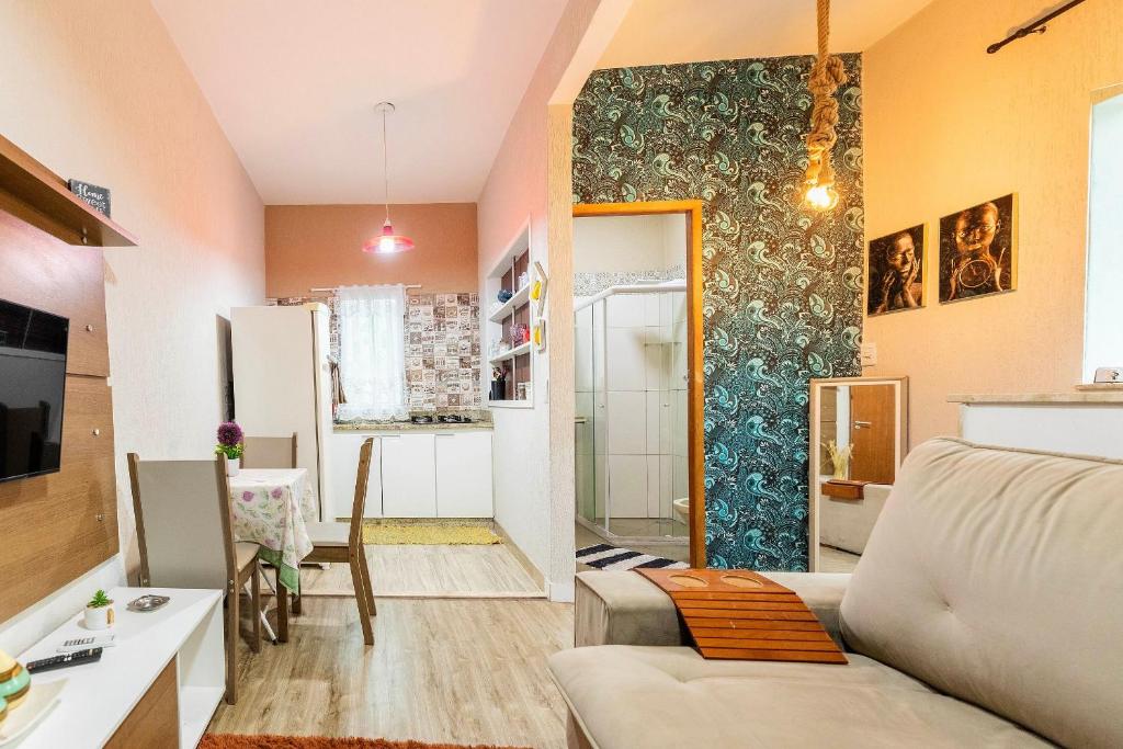 Una sala de estar con un sofá y una cocina. en Apartamento Moderno com vista para á principal, en Volta Redonda