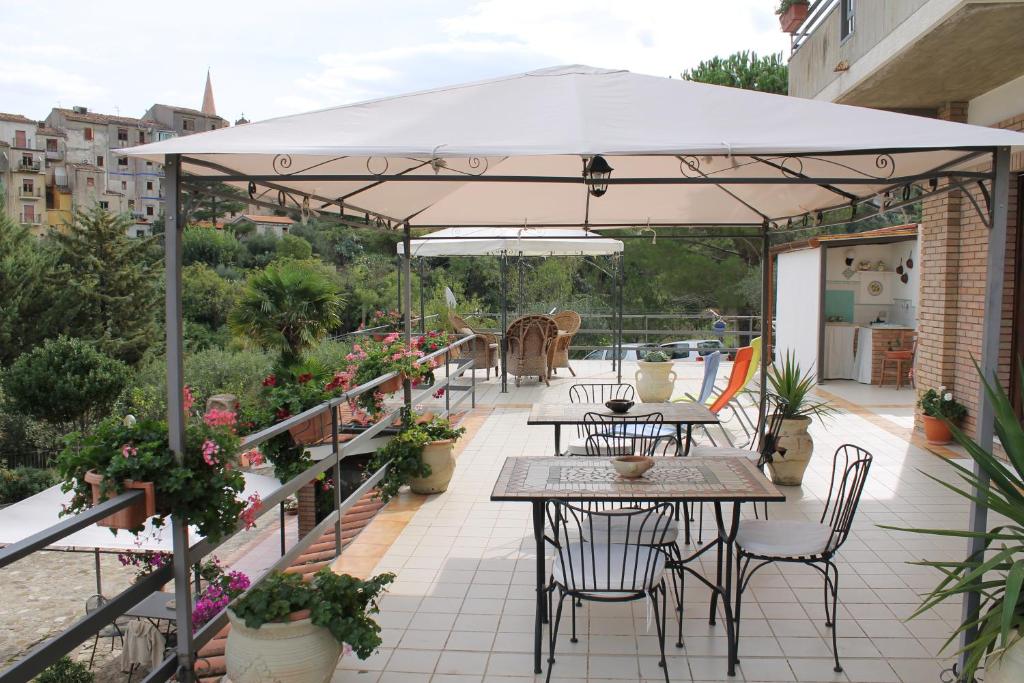 een patio met tafels en stoelen onder een parasol bij B&B Villa Letizia in Castelbuono