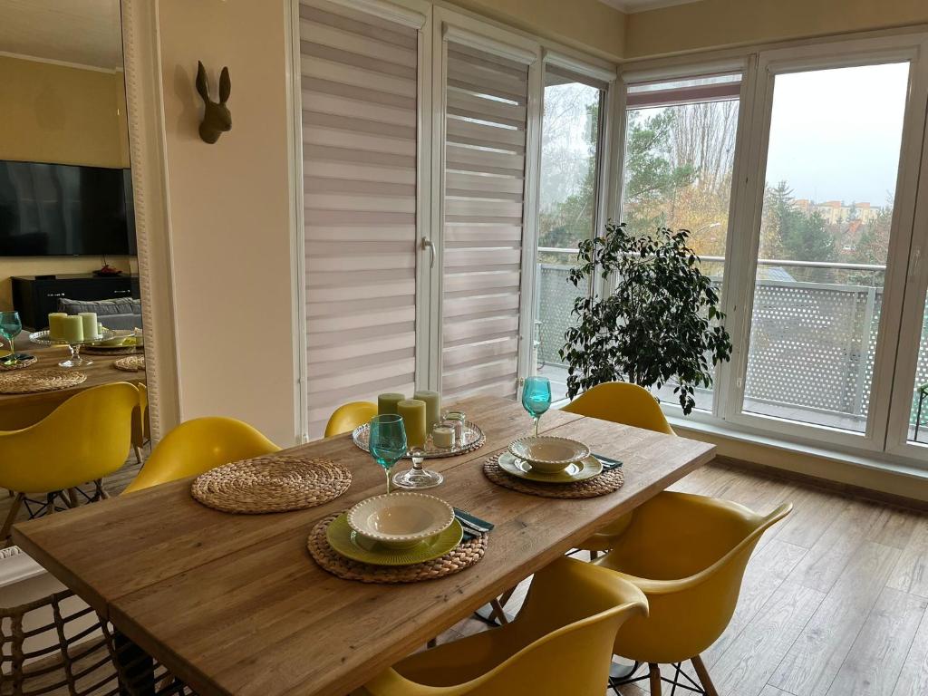 Un comedor con una mesa de madera y sillas amarillas. en Apartament Pruszków II, en Pruszków