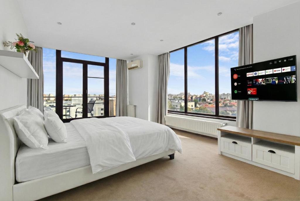 a white bedroom with a large bed and a flat screen tv at Uni88 Apart Hotel in Bucharest