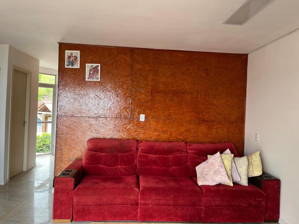 ein rotes Sofa in einem Zimmer mit einer Wand in der Unterkunft CasaRiva in Biguaçu