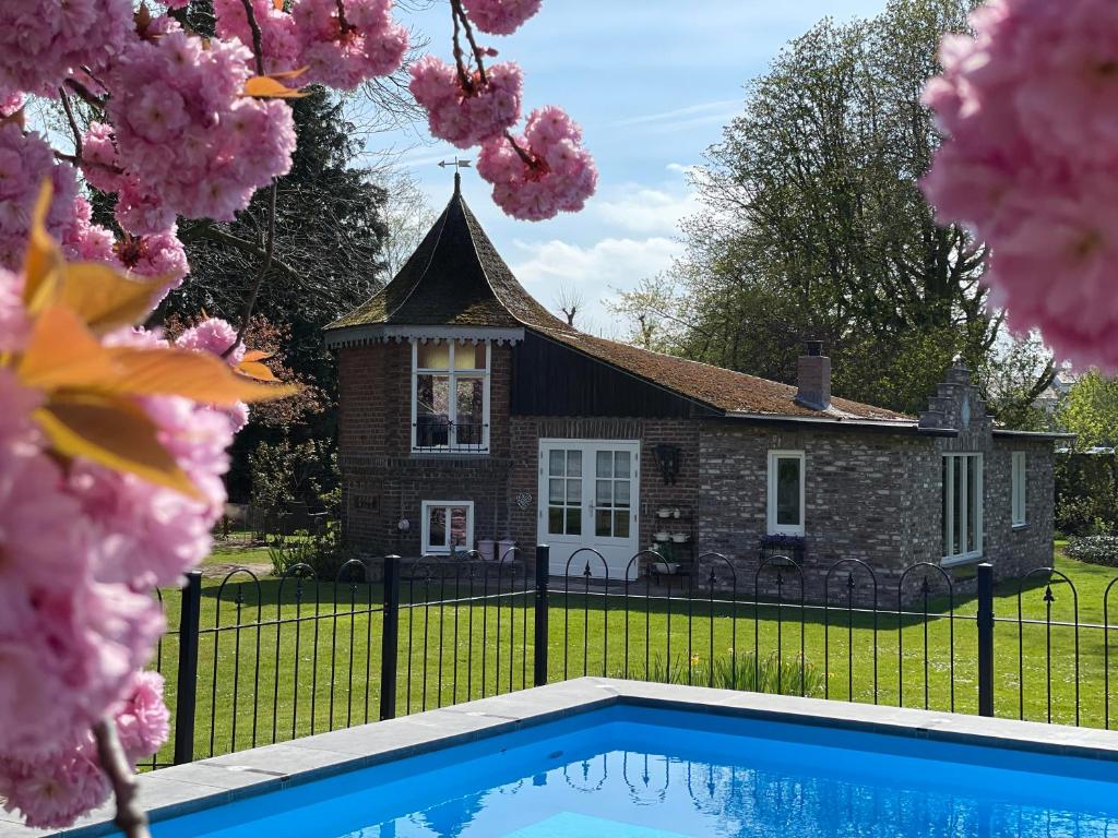 a house with a swimming pool in front of it at Petit Château luxe vakantiehuis, prive hottub en zwembad in Heythuysen